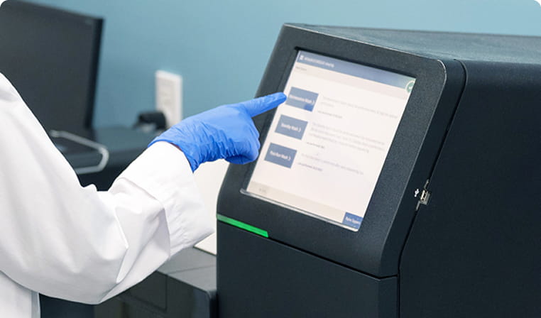 青い手袋をした研究者が、タッチパネル式の機器を操作している