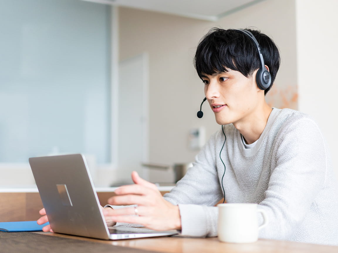 自宅でヘッドセットを付けオンライン会議に参加する男性のテレワークの様子