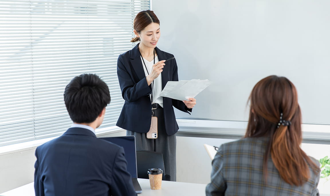 女性講師が社員に向けて研修やプレゼンテーションを行っている様子